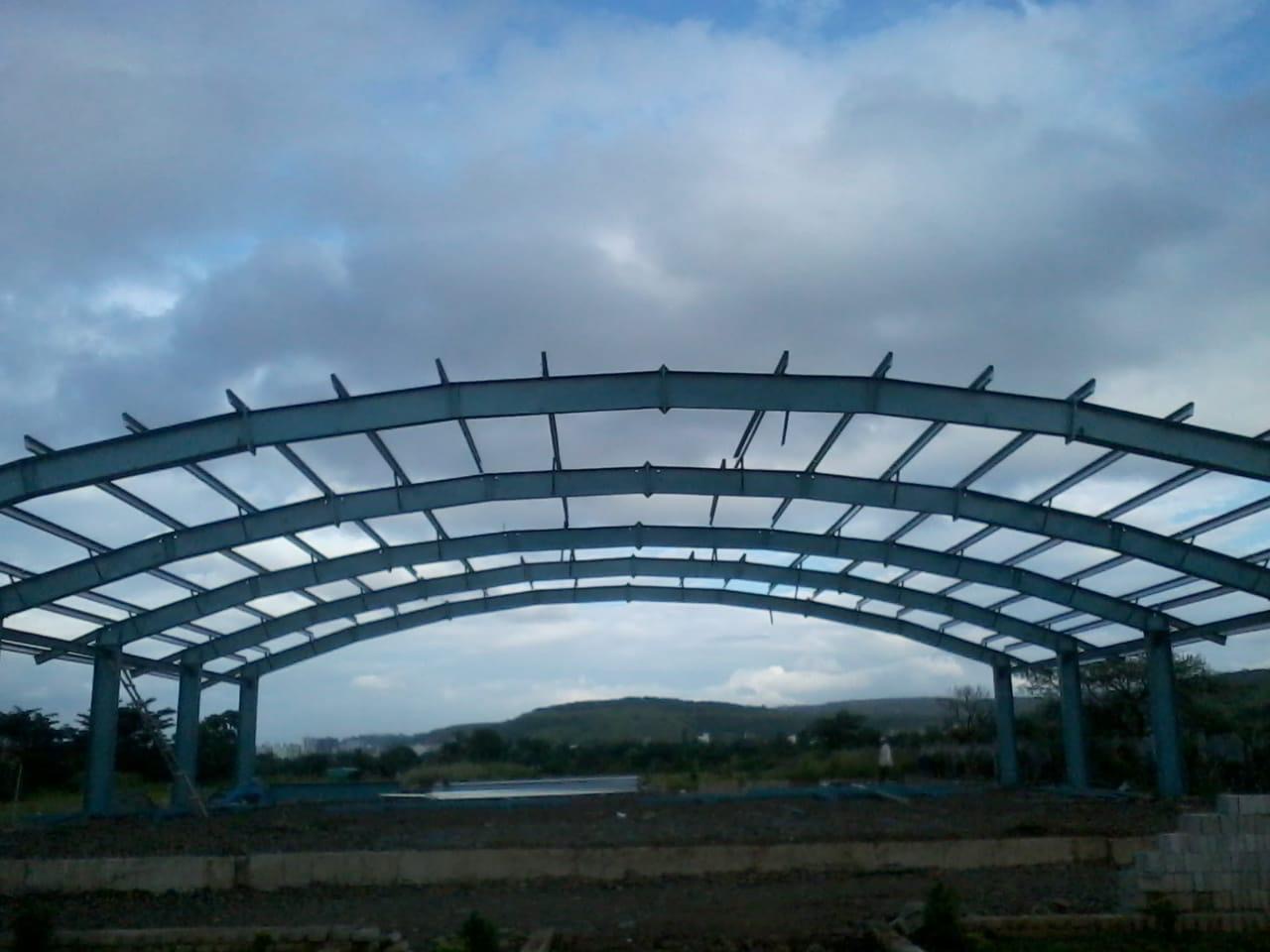 Curved arch roof steel frame under construction, showing detailed structural engineering