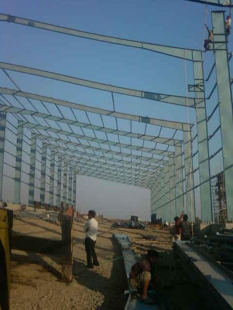 Erection team working on a steel frame structure with mobile crane