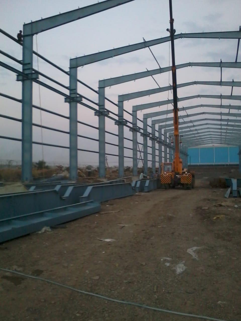 Steel frame erection at dusk with mobile crane