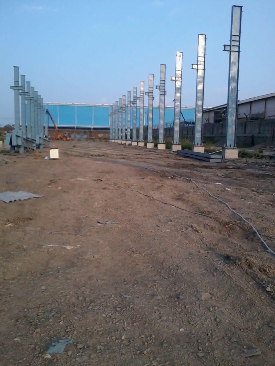 Rows of fabricated steel columns freshly erected on foundation base plates